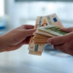 Deux mains avec des billets (Crédit : Alex.I)