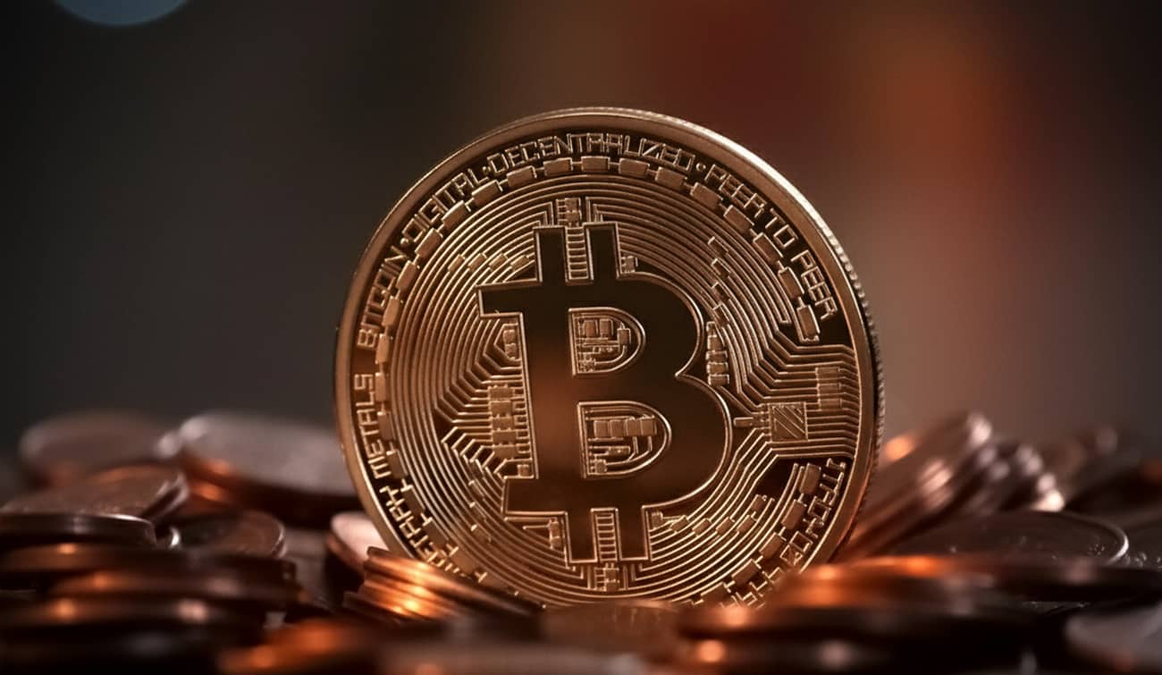 Un Bitcoin sur un tas de pièces de monnaie (Crédit : Alex.I)